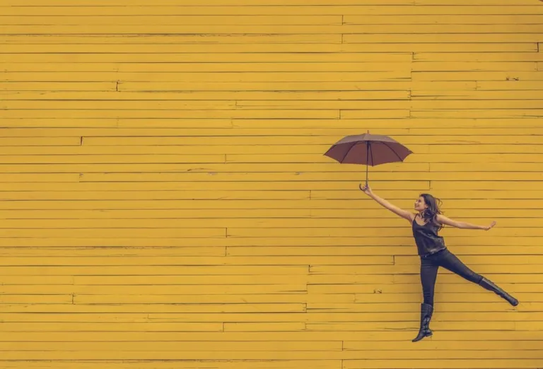 Frau mit einem Regenschirm auf dem gelben Hintergrung