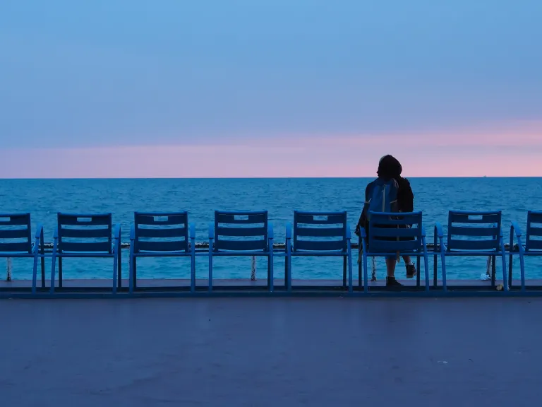 Person sitzt am Stuhl beim Wasser